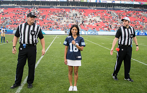 Argos football starting with a coin toss where cheerleader is wearing custom jersey.