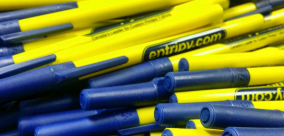 Pile of yellow and blue custom pens that are branded with Entripy's logo as custom promotional product.