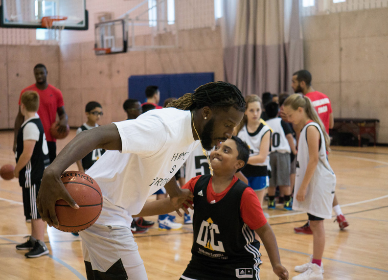 Toronto raptors playing basketball at the kids camp wearing white custom t-shirts and kids wearing custom jerseys.