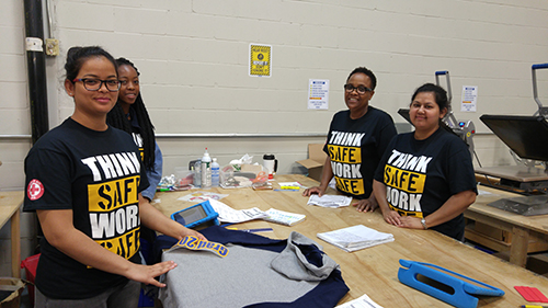 Entripy employees wearing customized t-shirts for Health & Safety week while doing heat transfer printing.