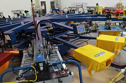 Custom printed t-shirts on screen-printing machines with custom logos.