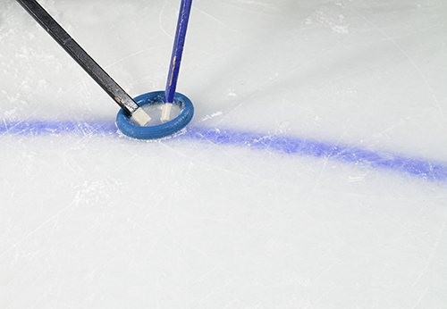 Rubber rings and stick displayed on the ice rink for the Ringette sport.