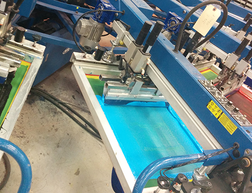 A screen-printing machine printing custom apparel orders with their customized logos.