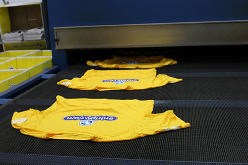 Printing custom t-shirts and putting them through a dryer for the last completing step.