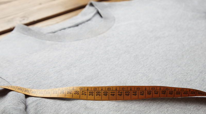 Measuring the size to custom print the logo on the grey custom t-shirt.