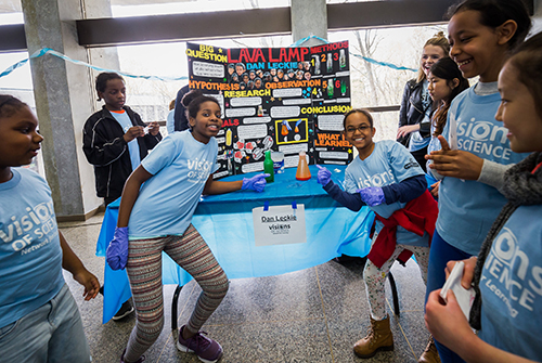 Youth showcasing their project at Vision of Science wearing customized t-shirts.