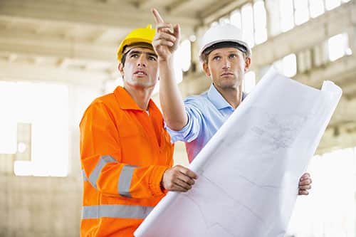 Employees visiting construction site discussing siteplan wearing custom uniforms.