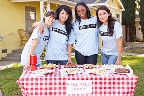 Volunteer custom t-shirts on a group of females for a bake sale.