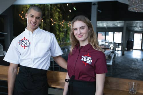 Employees displaying uniforms of custom coats and chef hats.